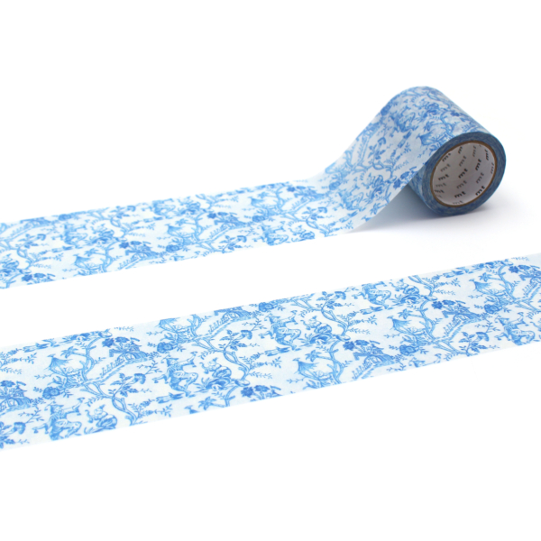 La bande XCOMM_MASKING TAPE FLEURS ET OISEAUX, qui présente un motif floral bleu, est partiellement déroulée sur un fond blanc, ce qui permet d'en apprécier la complexité. la marque Toile de Jouy