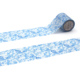 La bande XCOMM_MASKING TAPE FLEURS ET OISEAUX, qui présente un motif floral bleu, est partiellement déroulée sur un fond blanc, ce qui permet d'en apprécier la complexité. la marque Toile de Jouy