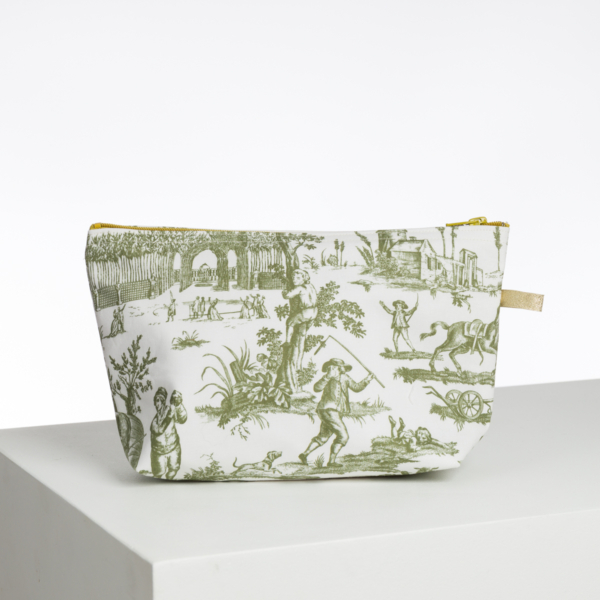 Le XCOMM_BIC BALLON PESTO est une pochette en tissu avec une fermeture éclair jaune et une toile pastorale verte imprimée de personnages, d'animaux et de scènes de la nature, sur une surface blanche avec un fond blanc uni. la marque Toile de Jouy