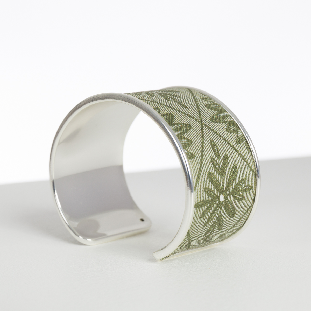 Le XCOMM_BIC BALLON PESTO est un bracelet manchette en argent présentant un motif de feuilles vertes et de flocons de neige sur fond blanc. la marque Toile de Jouy