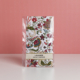 Un lot de sachets parfumés à la lavande « FANTAISIE INDIENNE » de la marque ETIQUETTE DE VOYAGE, ornés d'un motif floral et présentés dans un emballage en plastique transparent, est posé sur une surface blanche devant un fond rose. la marque Toile de Jouy