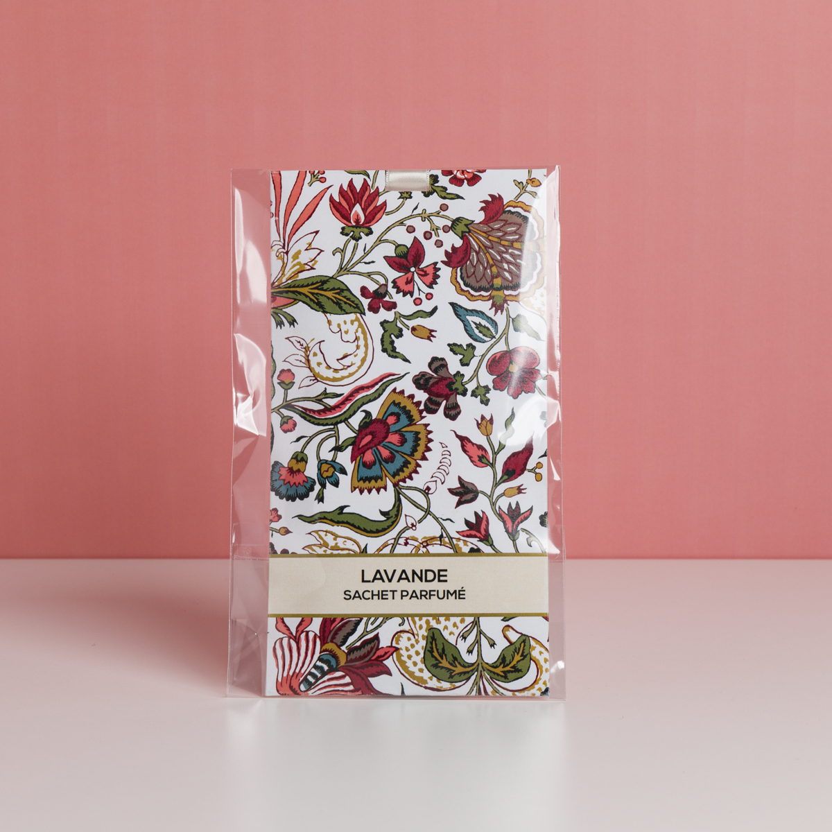 Un lot de sachets parfumés à la lavande « FANTAISIE INDIENNE » de la marque ETIQUETTE DE VOYAGE, ornés d'un motif floral et présentés dans un emballage en plastique transparent, est posé sur une surface blanche devant un fond rose. la marque Toile de Jouy