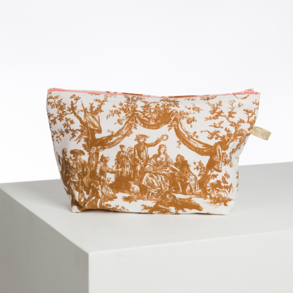 La pochette XCOMM_TROUSSE PENELOPE COURONNEMENT CUMIN est une pochette en tissu avec fermeture à glissière, présentant un imprimé de style vintage marron et blanc de personnes en tenue historique à l'extérieur sur un fond blanc uni. la marque Toile de Jouy