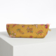 La XCOMM_CAPE DE PLUIE SEMIS DE FLEURS, une pochette à fermeture éclair jaune moutarde avec un motif floral rose, repose sur une surface blanche sur un fond simple. la marque Toile de Jouy