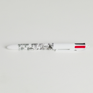 Un stylo à bille multicolore blanc avec des motifs noirs et blancs et "XCOMM_LUNCH BAG ESCARPOLETTE ROUGE" sur le corps, posé sur une surface blanche. Le stylo est doté de languettes de sélection d'encre rouge, noire et bleue. la marque Toile de Jouy