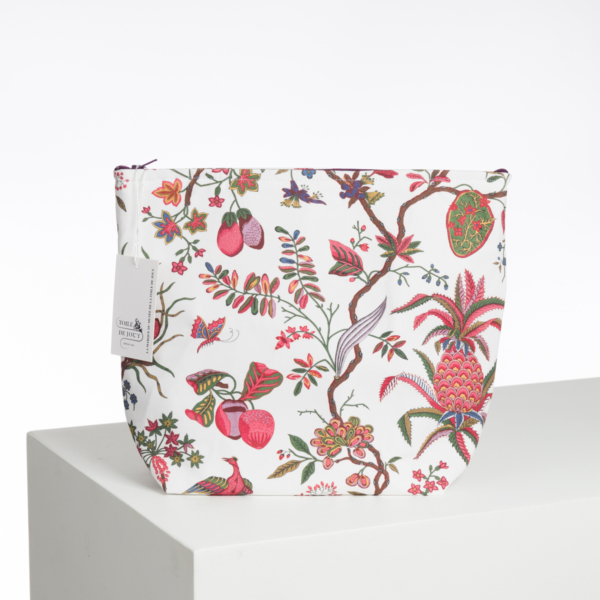 L'ABAT-JOUR SUR COMMANDE est une pochette blanche à fermeture éclair présentant un motif botanique et fruitier vibrant avec des ananas, des fraises, des fleurs et des feuilles, représentés sur une plate-forme blanche sur un fond uni. la marque Toile de Jouy