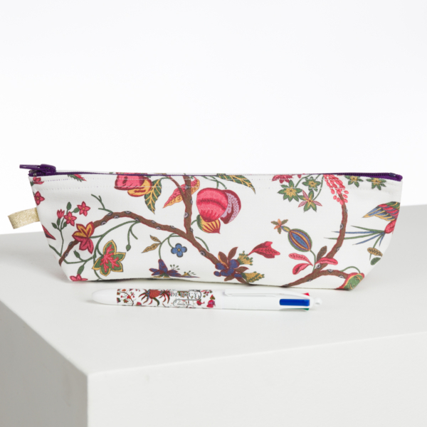 La pochette ABAT-JOUR SUR COMMANDE, ornée d'un motif floral et de branches colorées, est posée sur une surface blanche et un stylo floral assorti se trouve à l'avant. la marque Toile de Jouy