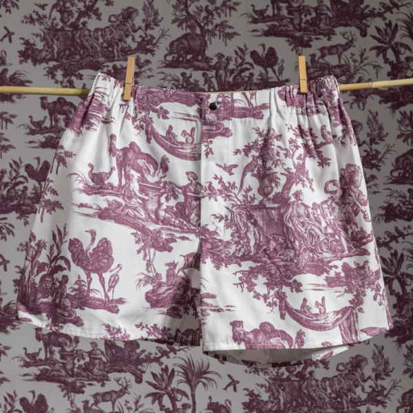 XCOMM_MICROFIBRE Le boxer ANANAS, avec son imprimé toile marron détaillé, est suspendu à une corde à linge avec des pinces à linge. Le papier peint qui se trouve derrière est assorti au motif complexe, ce qui permet au short de se fondre dans l'arrière-plan. la marque Toile de Jouy