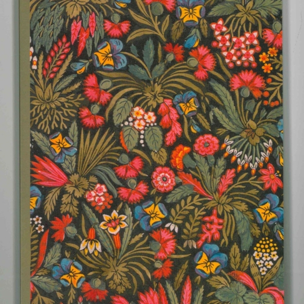 Le carnet XCOMM_CARNET A5 BLEUETS présente une couverture avec un motif floral dense et coloré représentant des fleurs rouges, jaunes, bleues et roses avec des feuilles vertes sur un fond sombre. la marque Toile de Jouy