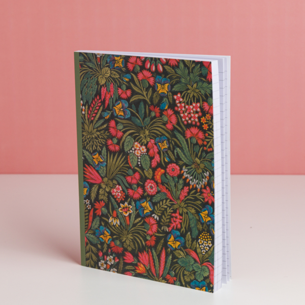 L'EMPREINTE SOUS PASSE-PARTOUT "BONNES HERBES - BLEUETS" est un carnet de notes sur pied avec une couverture florale vibrante dans les tons rouge, jaune et bleu. Il contient du papier millimétré et se présente sur un fond rose. la marque Toile de Jouy