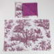 Le XCOMM_SET DE TABLE /2 FLEURS STYLISEES SAUGE comprend un set de table blanc et une serviette pliée avec des motifs floraux stylisés en sauge ; la serviette présente également un côté en sauge unie. Les deux sont disposés sur un fond blanc. la marque Toile de Jouy
