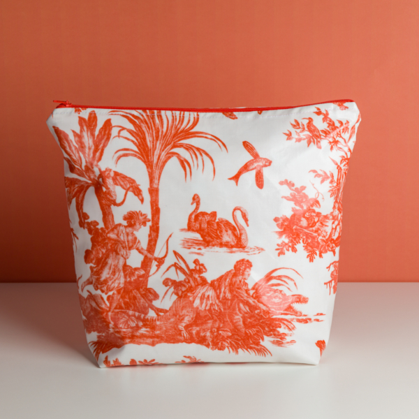 La « XCOMM_GRANDE TROUSSE DE TOILETTE 4 PARTIES MANDARINE ENDUITE » est une trousse blanche à fermeture éclair, ornée d'un imprimé « toile » orange représentant des cygnes, des palmiers et des personnages sur un fond orange assorti. la marque Toile de Jouy