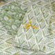 Deux serviettes XCOMM_SERVIETTES/ 6 CHARDON SAUGE aux imprimés botaniques verts reposent sur une surface assortie, ornée de fleurs et de feuillages jaunes pour ajouter de la couleur et de la texture. la marque Toile de Jouy