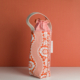 Le XCOMM_SAC ISOTHERME FLEURS MANDARINE est un sac en tissu à motif floral rouge et blanc avec une poignée crème et un cordon vichy rouge, présenté à la verticale sur un fond rouge assorti. la marque Toile de Jouy