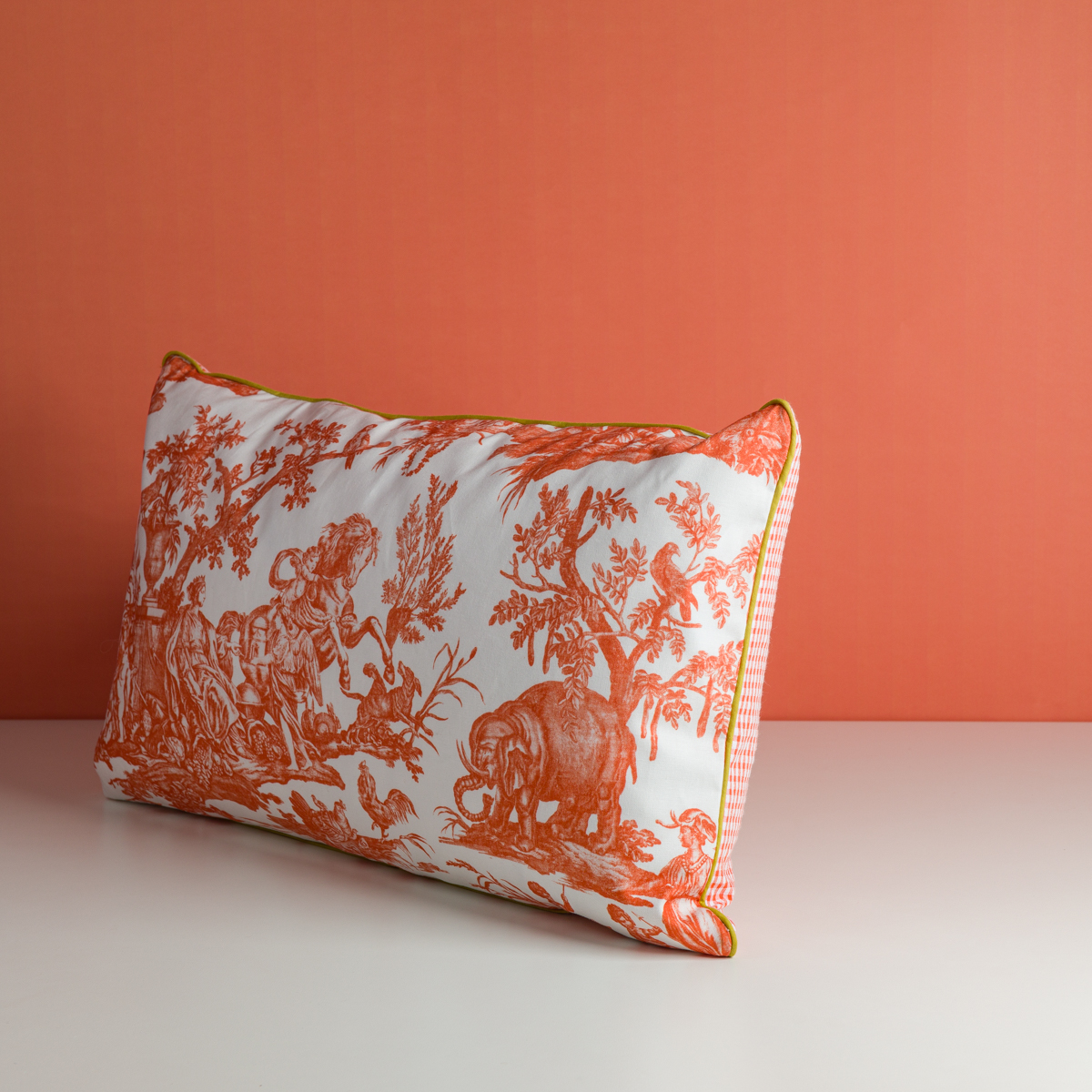 L'oreiller XCOMM_COUSSIN 30X50 FLEURS MANDARINE, qui présente un motif de toile florale orange et blanche avec un liseré jaune, est présenté sur une surface blanche sur un fond orange uni. la marque Toile de Jouy