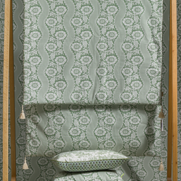 Le XCOMM_MATELAS DE REPOS FLEURS STYLISEES SAUGE 190X90, avec son motif floral vert clair, est drapé sur un support en bois et associé à des coussins assortis. Les motifs coordonnés au mur et au sol complètent l'aspect décoratif cohérent. la marque Toile de Jouy