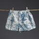 Le XCOMM_COUSSIN 30X50 ESCARPOLETTE BLEU, orné d'un motif de toile bleue, est suspendu à une tige de bambou à l'aide de deux pinces à linge en bois, sur un fond uni foncé. la marque Toile de Jouy