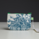 Une petite pochette en tissu intitulée « XCOMM_COUSSIN 30X50 ESCARPOLETTE BLEU » est dotée d’une fermeture à glissière verte et d’une illustration bleue représentant une figure classique entourée d’oiseaux, de ciseaux et de feuillage. Elle comporte également une languette à carreaux verts et est munie d’une étiquette blanche cousue. la marque Toile de Jouy