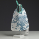 Un « XCOMM_COUSSIN 30X50 ESCARPOLETTE BLEU » est présenté sur un présentoir blanc devant un fond sombre. Le coussin est confectionné dans un tissu blanc orné de motifs de toile bleue et doté d’une poignée rayée verte ; il est orné d’une étiquette portant la mention « Chez Diane ». la marque Toile de Jouy