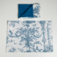 Un coussin XCOMM_COUSSIN 30X50 ESCARPOLETTE BLEU, orné d’un motif bleu et blanc représentant des oiseaux et du feuillage, accompagné d’une serviette pliée assortie présentant un côté bleu uni. Les deux articles sont disposés sur un fond blanc, l’étiquette du coussin étant visible. la marque Toile de Jouy