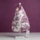 Le modèle XCOMM_BAVOIR 4 APRTIES AMARANTE est un sac en tissu blanc orné d'un imprimé violet représentant des animaux et des paysages, agrémenté d'une poignée en ruban et d'une étiquette, présenté sur un présentoir blanc devant un fond violet. la marque Toile de Jouy