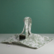 Le XCOMM_SAC A PAIN OFFRANDE SAUGE, un fourre-tout en tissu souple avec des imprimés botaniques verts, deux poignées et une étiquette blanche, est présenté sur une surface blanche sur fond vert. la marque Toile de Jouy